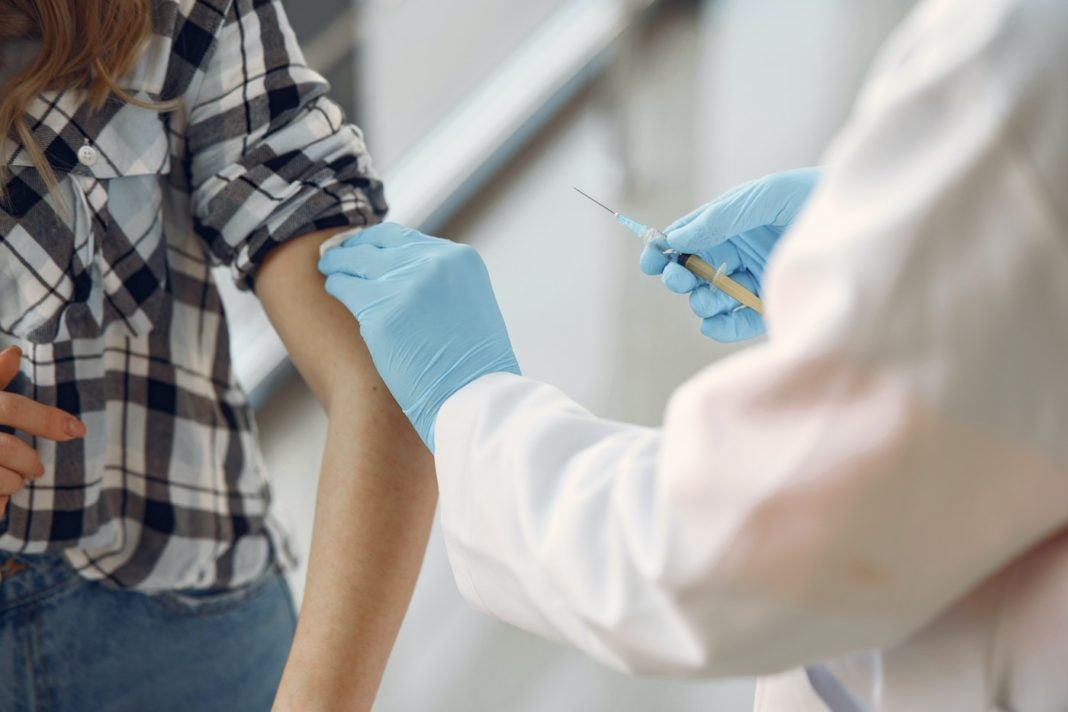 Image of doctor administering COVID-19 vaccine to patient's arm.