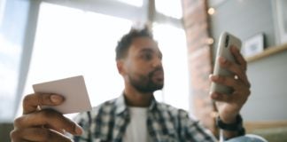 Image of business person holding a credit card in one hand and a credit card in the other.